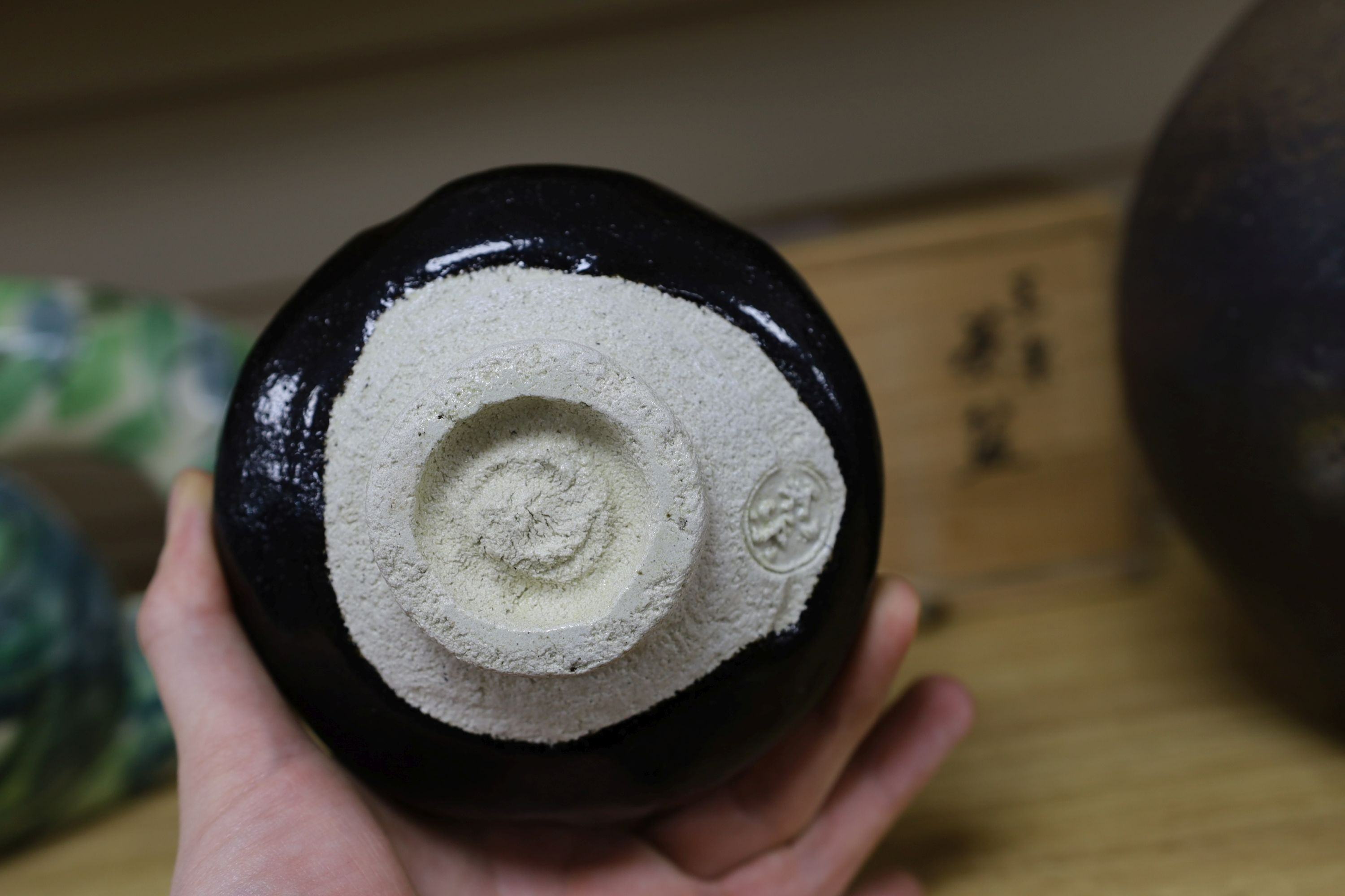 Japanese studio pottery: a boxed black glaze stoneware unomi tea bowl, with impressed mark, together with a ovoid vase, marked, 21cm tall